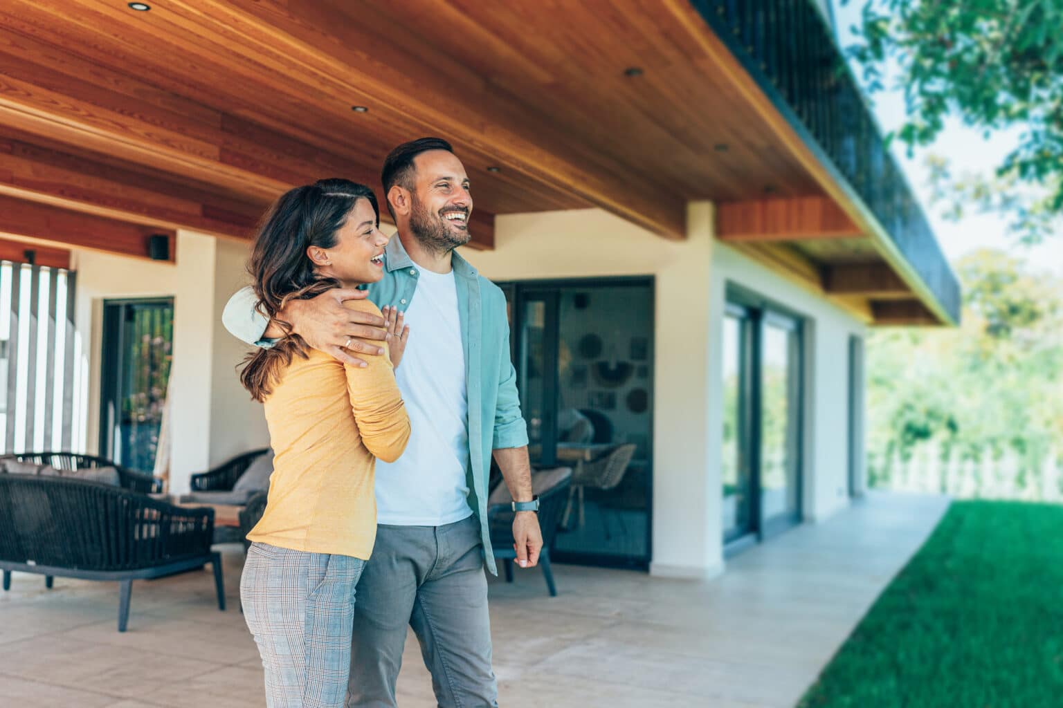 Un couple devant une propriété avec terrasse et jardin